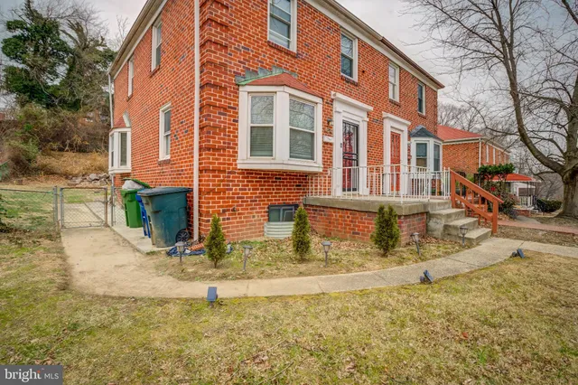 a view of a brick house with a yard and large tree