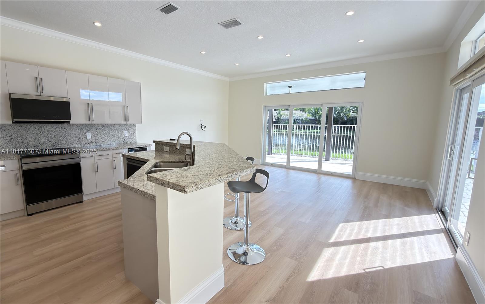 4221 Laurel Ridge Circle Weston, FL 33331 - Photo 12 of 57 a kitchen with stainless steel appliances granite countertop a stove top oven a sink dishwasher and a refrigerator with wooden floor