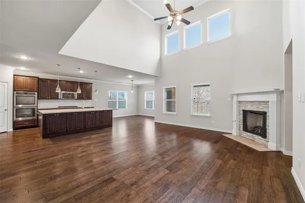 a view of a kitchen with a sink a fireplace a ceiling fan and wooden floor