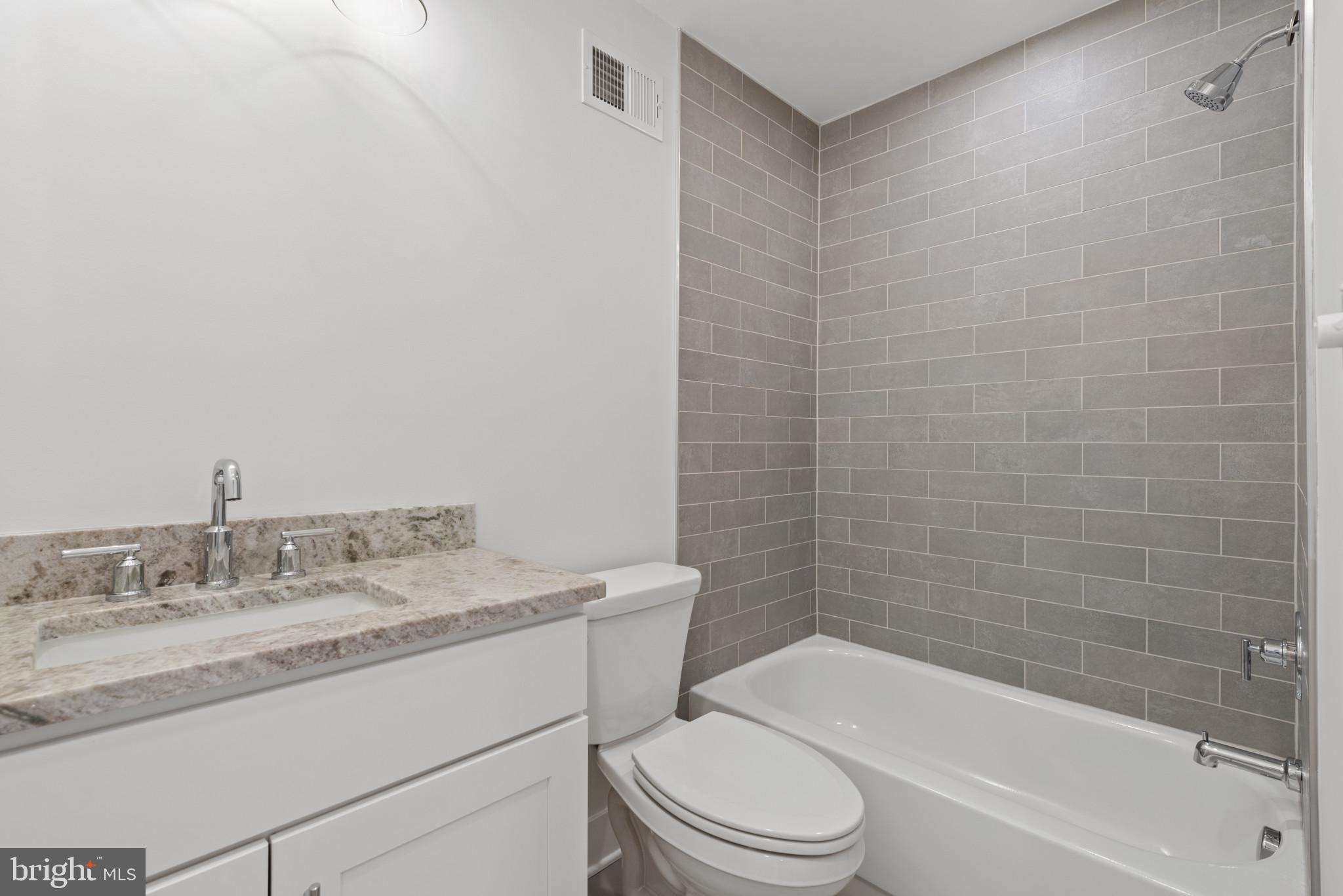 1005 Riverside Avenue Baltimore, MD 21230 - Photo 21 of 29 a bathroom with a granite countertop bathtub shower sink vanity and toilet