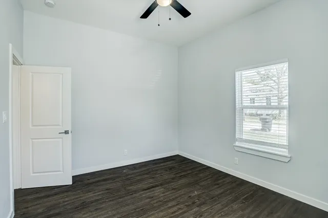 an empty room with wooden floor cabinet and windows