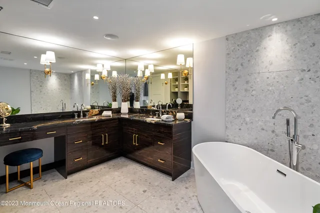 a bathroom with a tub a sink double vanity and a shower