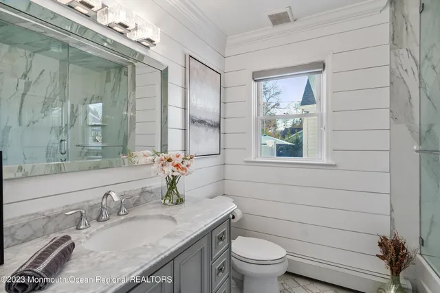 a bathroom with a granite countertop sink a large mirror and a toilet