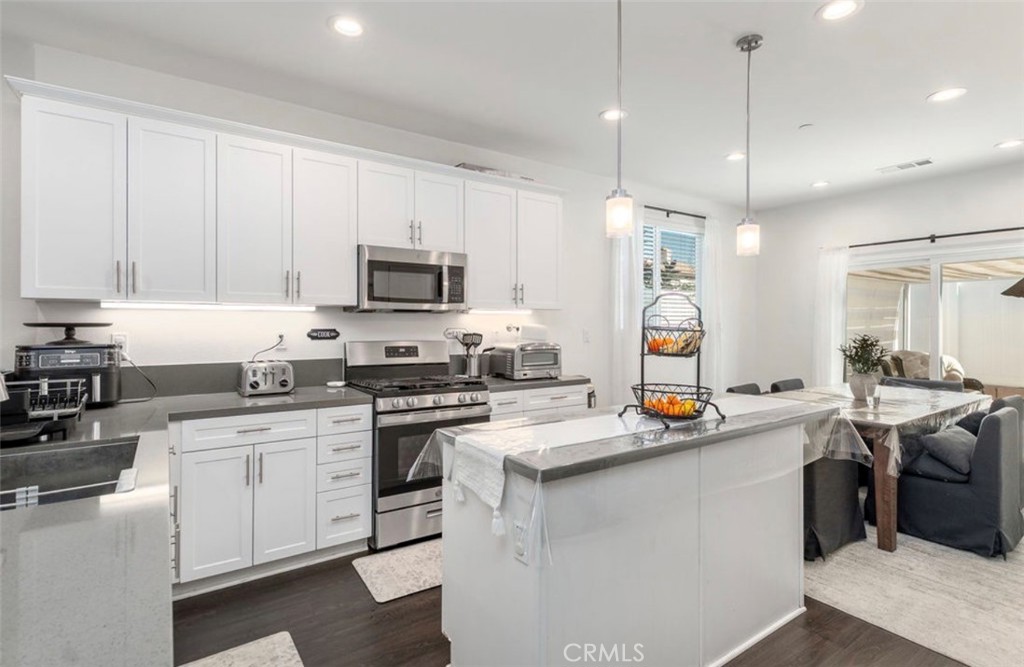 455 East Orchard Street Rialto, CA 92376 - Photo 17 of 22 a kitchen with stainless steel appliances granite countertop a sink stove a refrigerator and white cabinets with wooden floor
