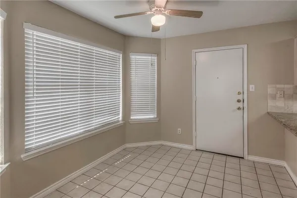 a view of an empty room with window and chandelier fan