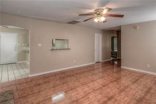 a view of an empty room with chandelier fan