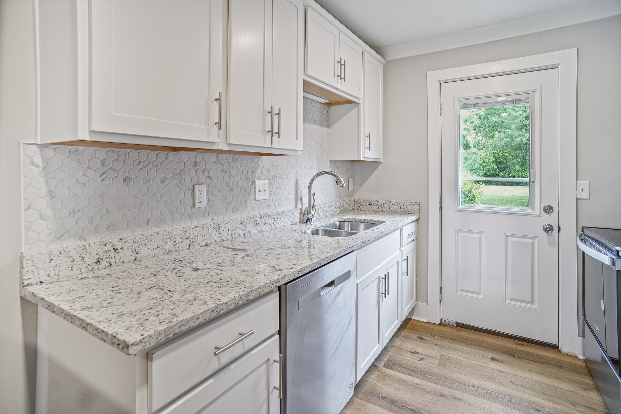 a kitchen with granite countertop a sink and dishwasher with wooden floor