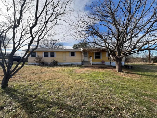 a front view of house with yard and trees around