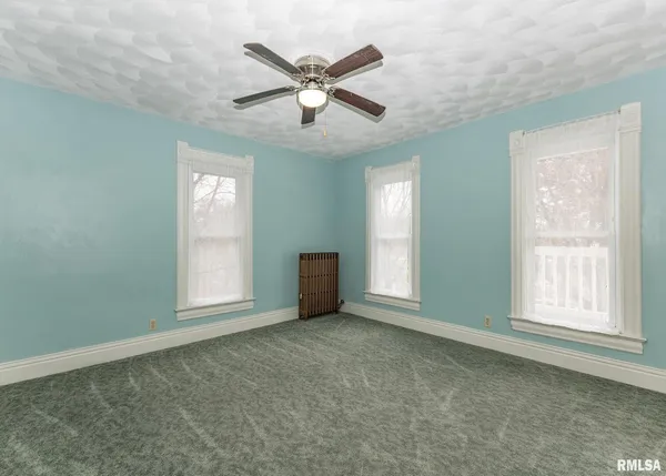 an empty room with ceiling fan and windows