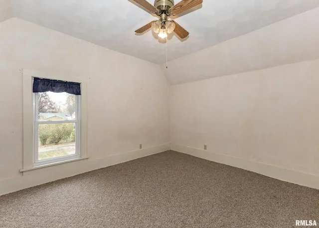 an empty room with a window and a fan