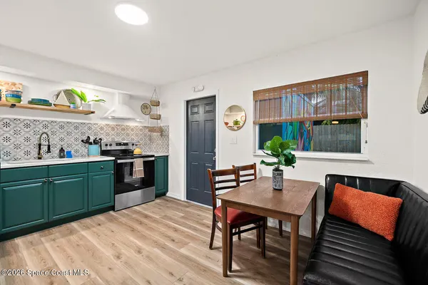 a kitchen with stainless steel appliances granite countertop a stove a sink dishwasher a dining table and chairs with wooden floor