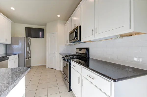a kitchen with stainless steel appliances granite countertop white cabinets a stove top oven a sink and dishwasher