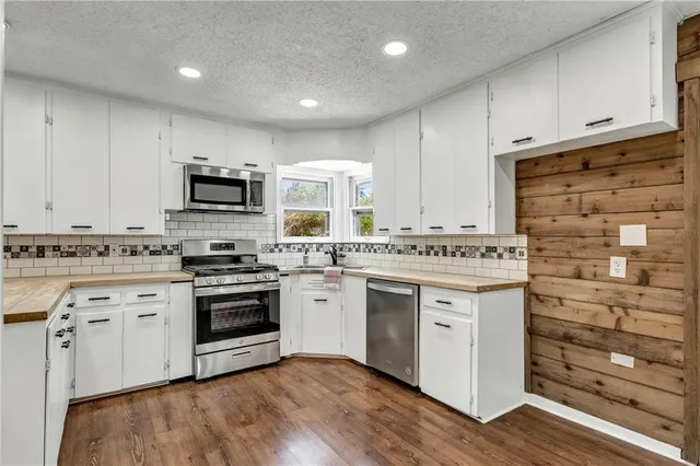 a kitchen with granite countertop white cabinets stainless steel appliances and sink