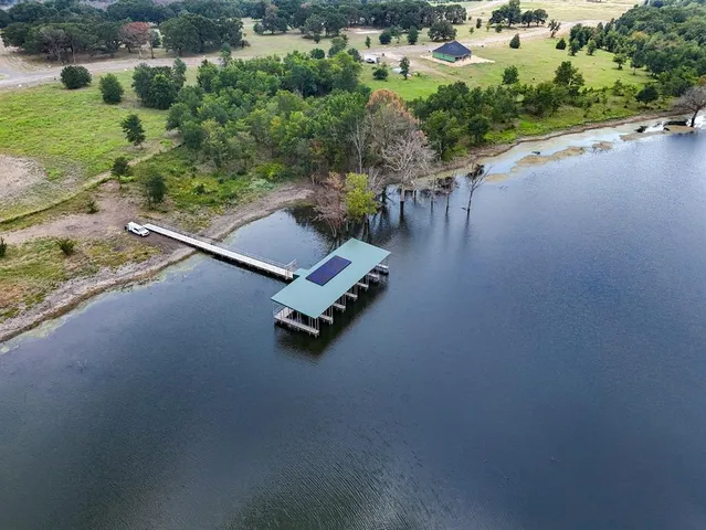 an aerial view of a swimming pool with outdoor seating and yard