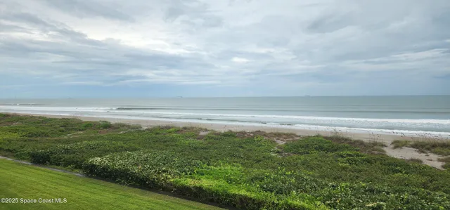a view of kitchen and empty room with wooden floor