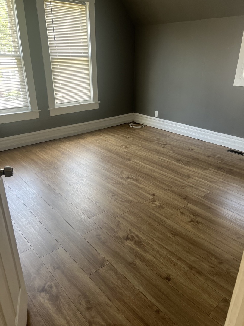 12124 South Normal Avenue Chicago, IL 60628 - Photo 18 of 36 an empty room with wooden floor and windows