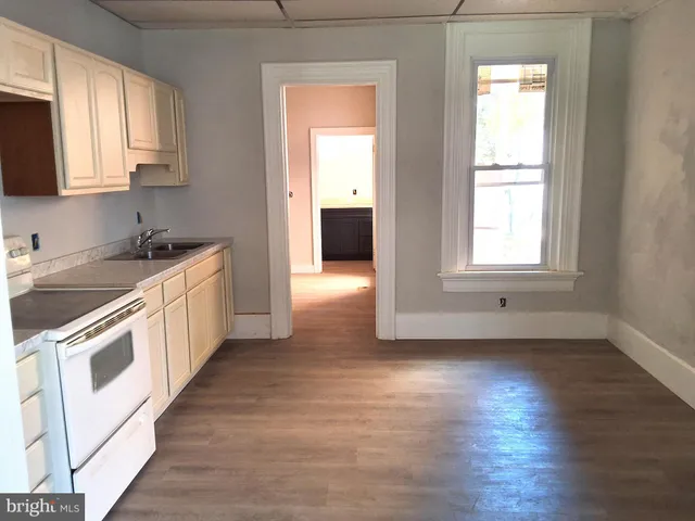 a kitchen with a white cabinets and wooden floor