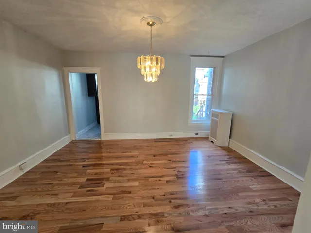 a view of an empty room with wooden floor and window
