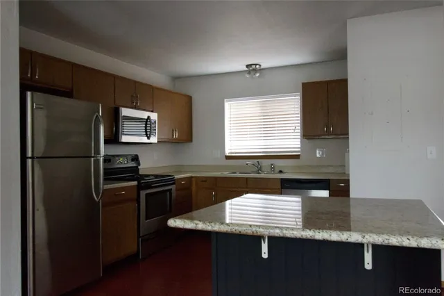 a kitchen with granite countertop stainless steel appliances a sink stove and refrigerator