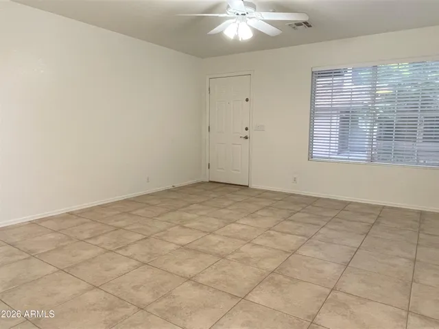 an empty room with a chandelier fan and windows