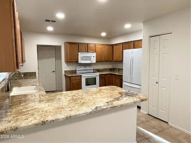 a kitchen with kitchen island granite countertop a refrigerator and a sink