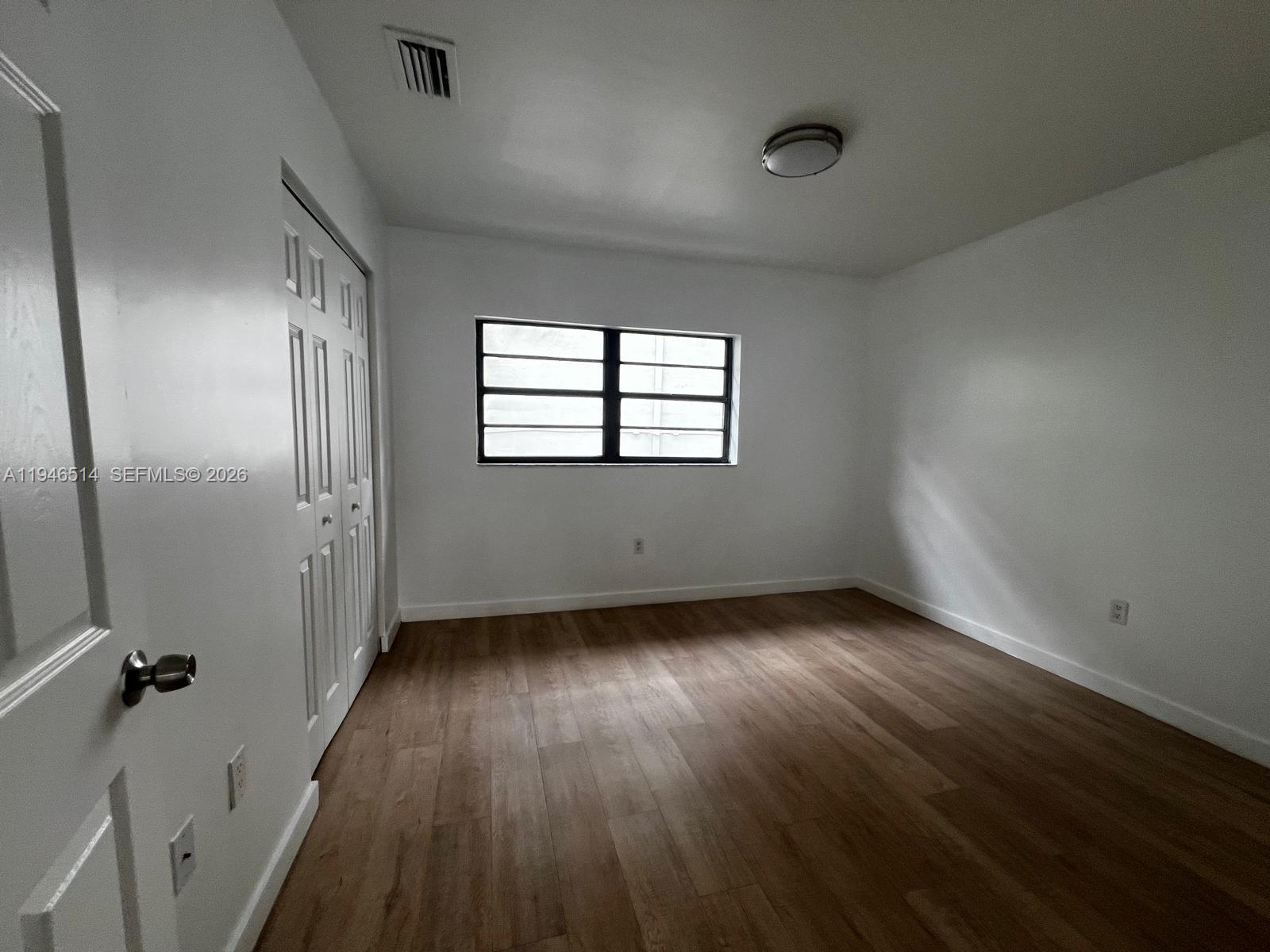 324 West 74th Place, Unit 6 Hialeah, FL 33014 - Photo 12 of 13 an empty room with wooden floor and windows