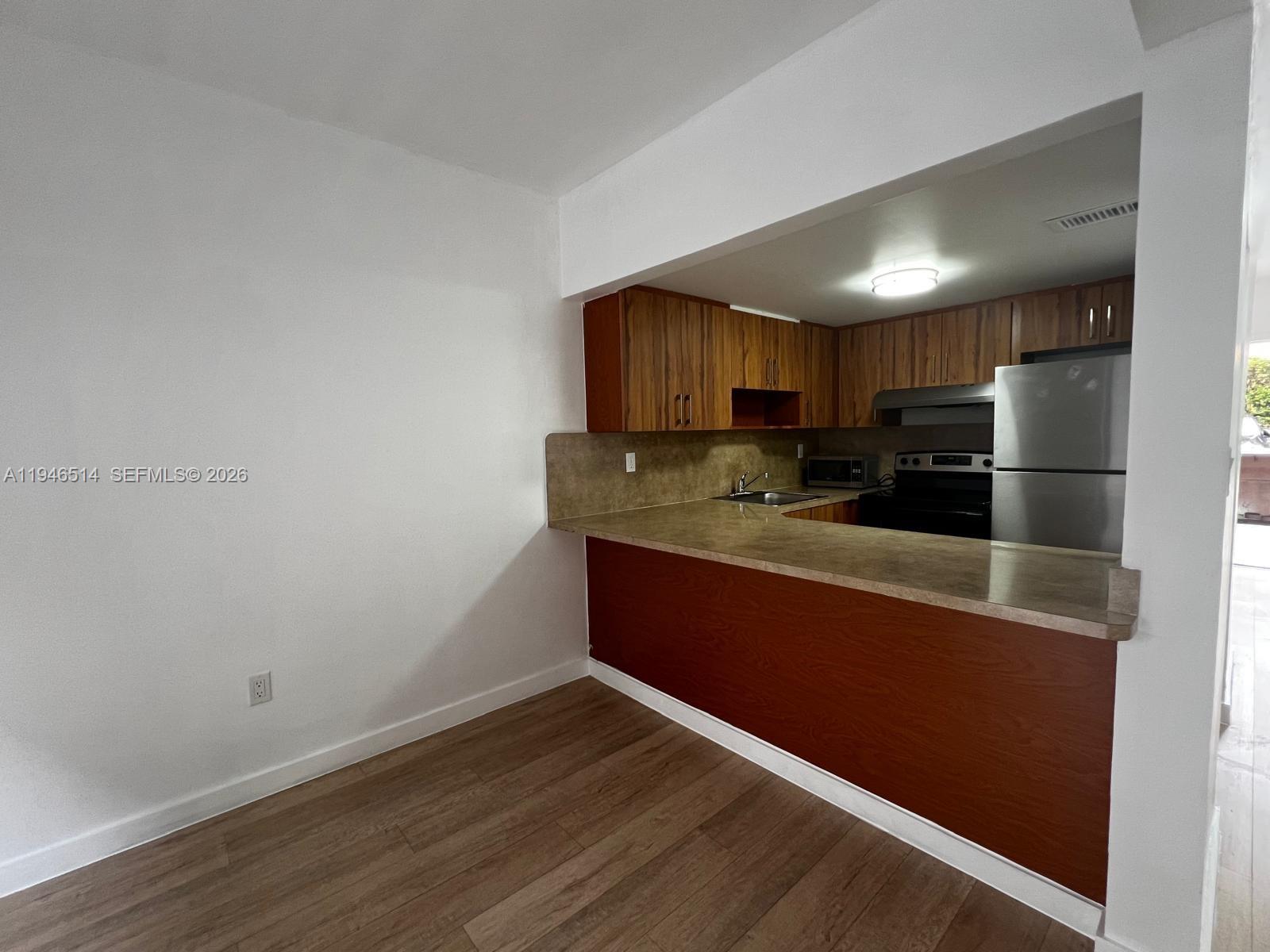 324 West 74th Place, Unit 6 Hialeah, FL 33014 - Photo 2 of 13 a kitchen with wooden cabinets and a refrigerator