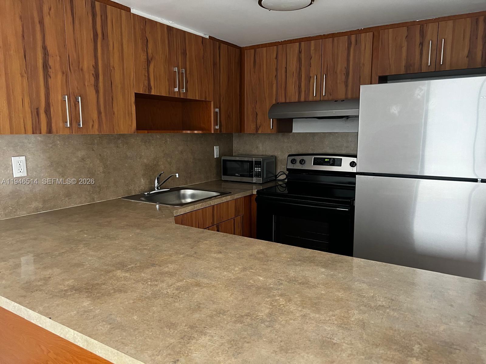 324 West 74th Place, Unit 6 Hialeah, FL 33014 - Photo 5 of 13 a kitchen with granite countertop a refrigerator stove top oven a sink and dishwasher