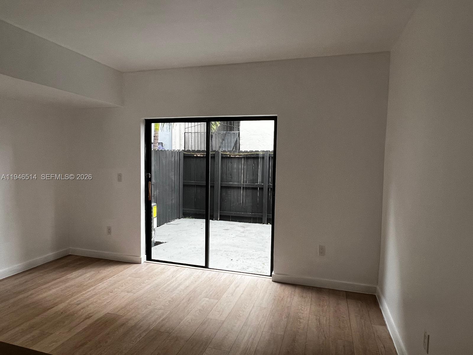 324 West 74th Place, Unit 6 Hialeah, FL 33014 - Photo 6 of 13 an empty room with wooden floor and sliding door
