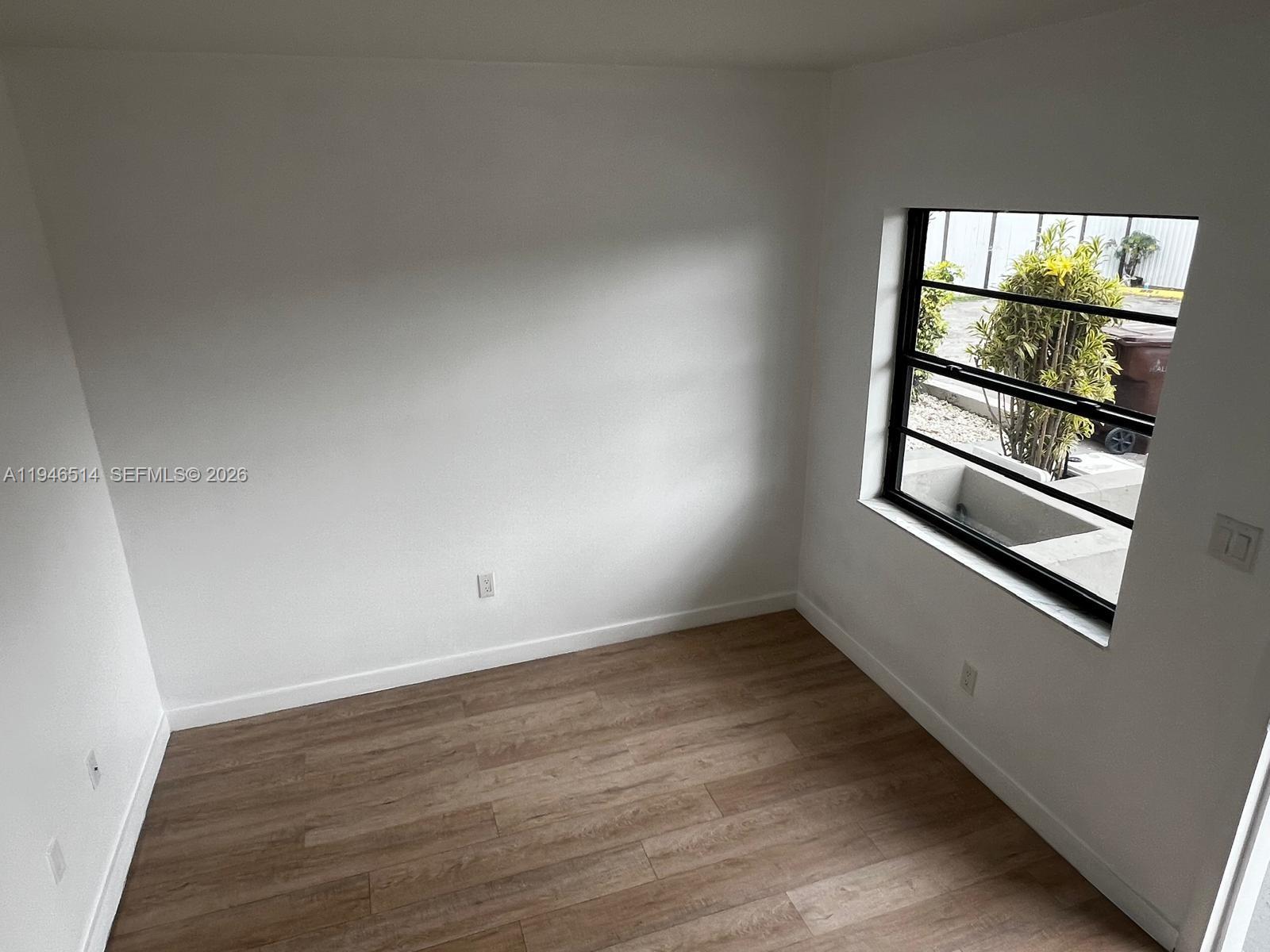 324 West 74th Place, Unit 6 Hialeah, FL 33014 - Photo 7 of 13 an empty room with wooden floor and windows