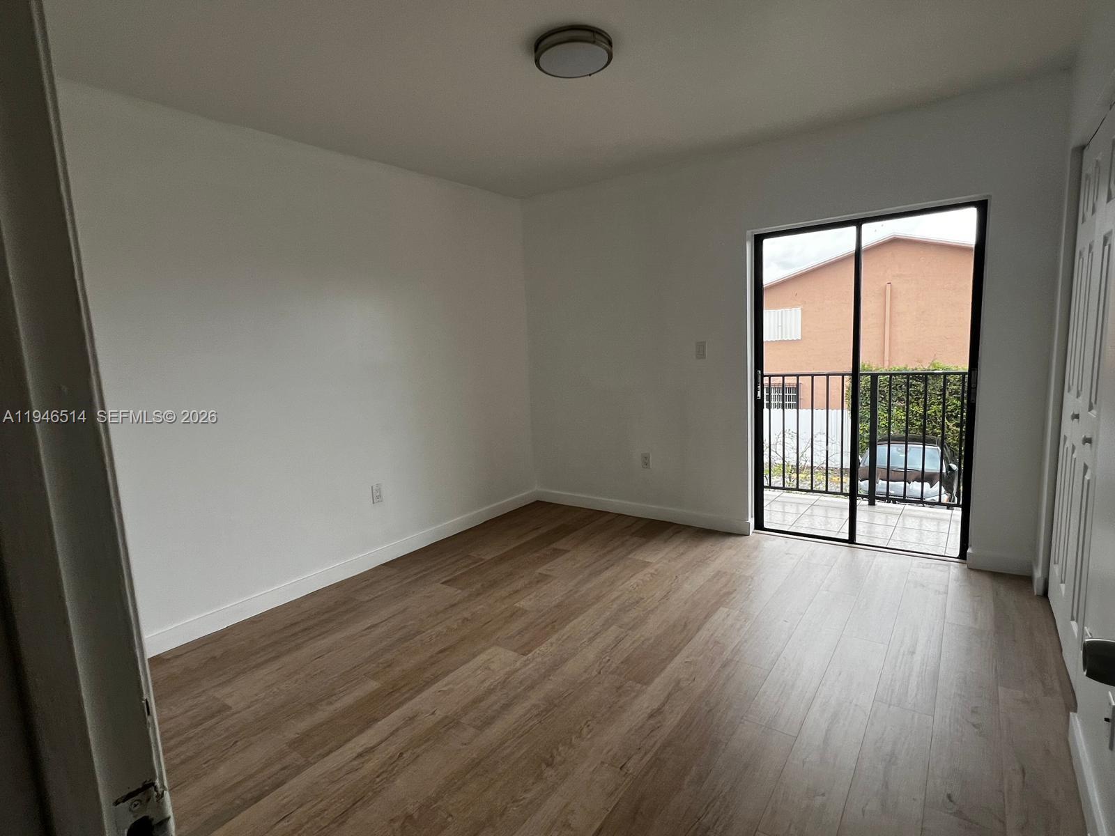 324 West 74th Place, Unit 6 Hialeah, FL 33014 - Photo 9 of 13 an empty room with wooden floor and windows