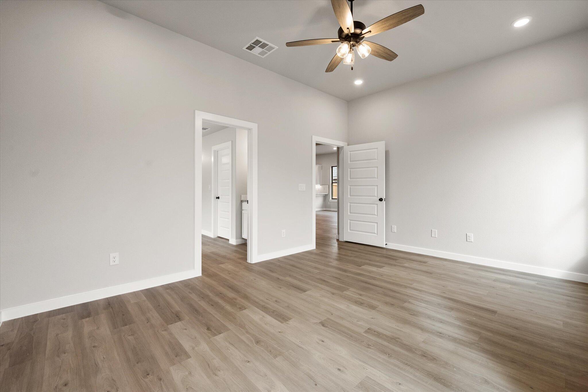 6825 54th Street Lubbock, TX 79407 - Photo 13 of 22 an empty room with wooden floor ceiling fan and windows
