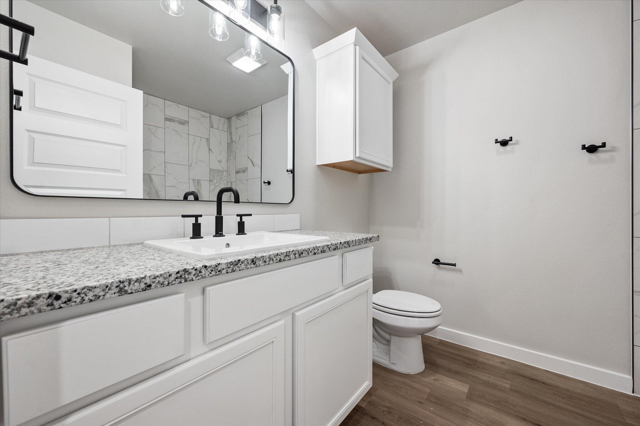 6825 54th Street Lubbock, TX 79407 - Photo 20 of 22 a bathroom with a granite countertop sink a toilet and a mirror