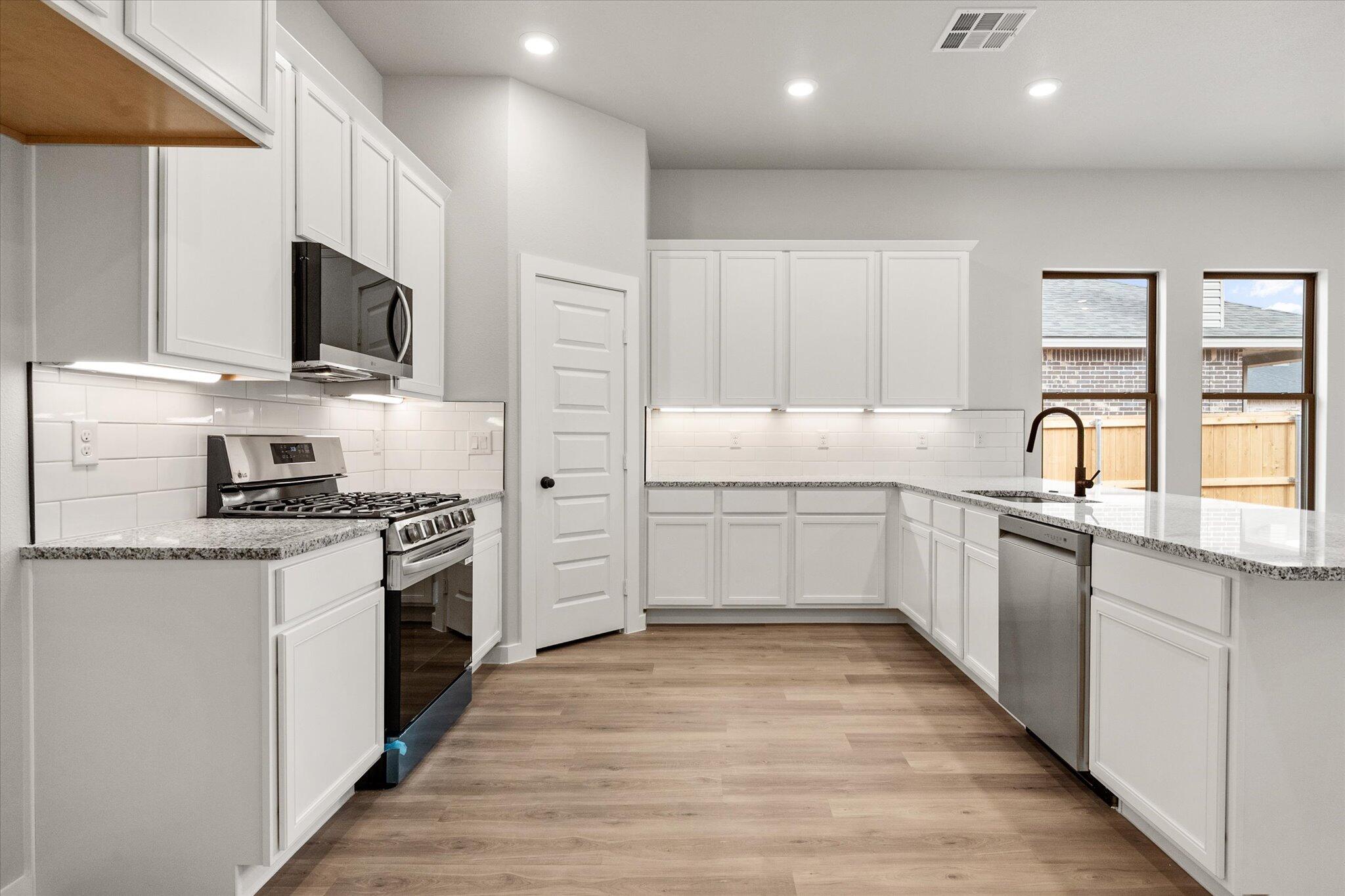 6825 54th Street Lubbock, TX 79407 - Photo 4 of 22 a kitchen with stainless steel appliances white cabinets a sink and a stove