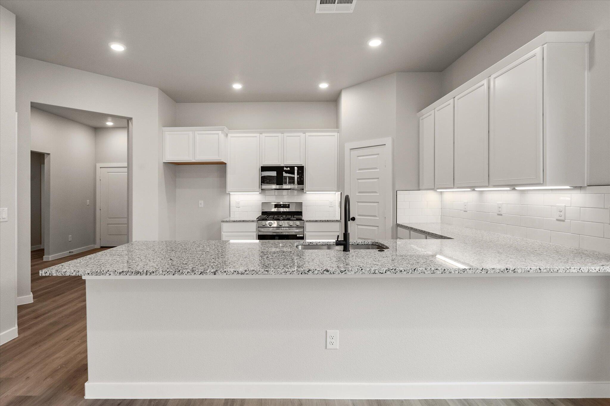 6825 54th Street Lubbock, TX 79407 - Photo 7 of 22 a large kitchen with granite countertop a sink a counter top space stainless steel appliances and cabinets