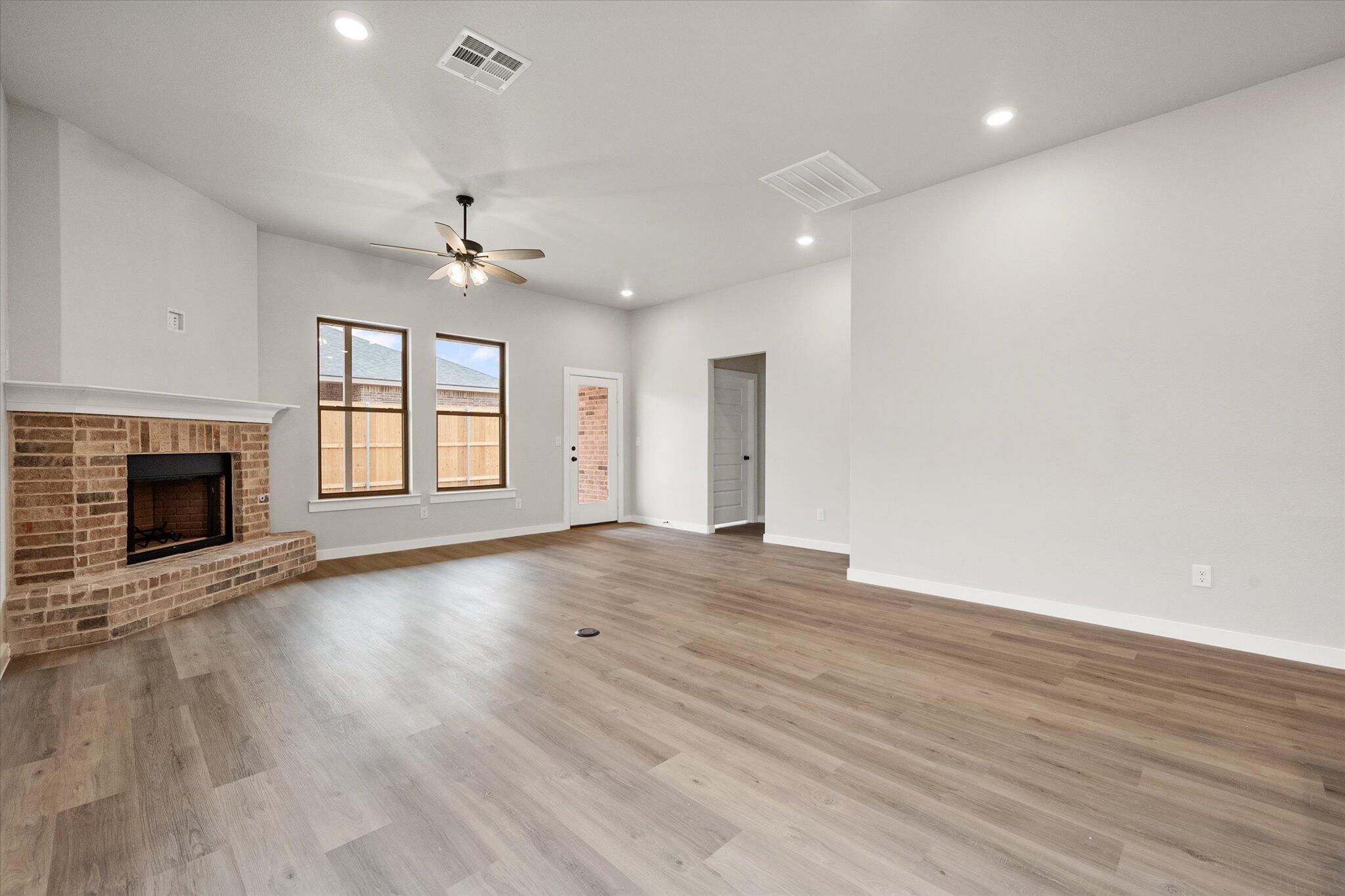 6825 54th Street Lubbock, TX 79407 - Photo 9 of 22 an empty room with wooden floor fireplace and windows