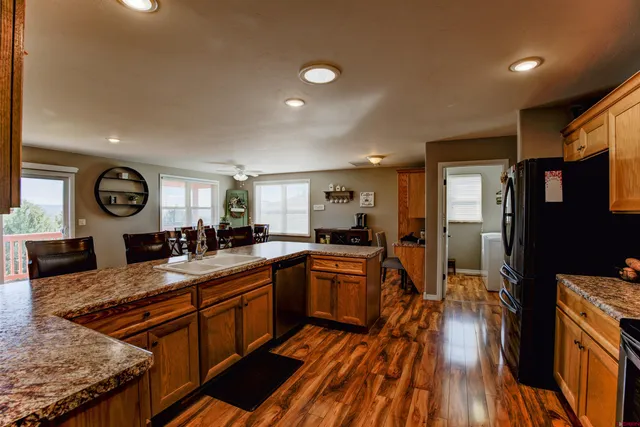 a kitchen with stainless steel appliances granite countertop sink stove refrigerator and wooden floor