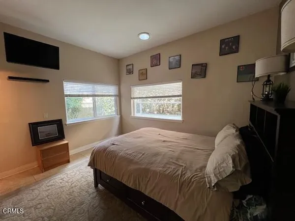 a bedroom with a bed a painting on the wall and a window