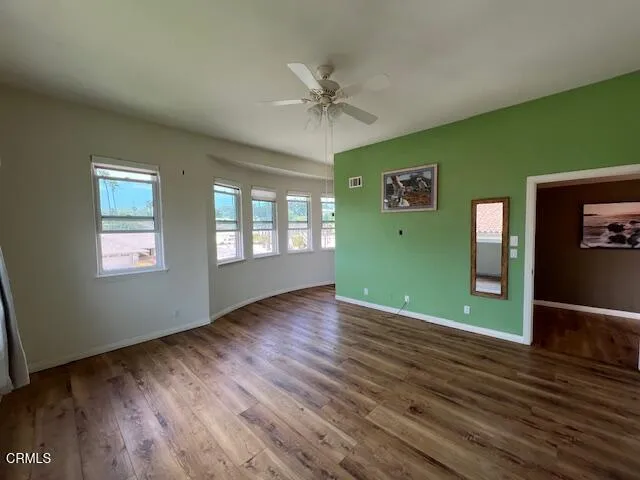 a view of an empty room with window and wooden floor