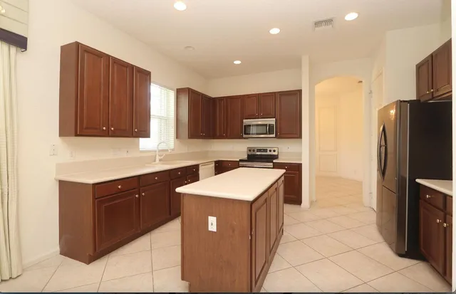 a kitchen with kitchen island granite countertop wooden cabinets stainless steel appliances a sink and a counter top space