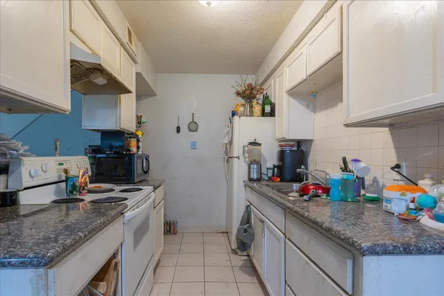 a kitchen with granite countertop a sink dishwasher stove and cabinets