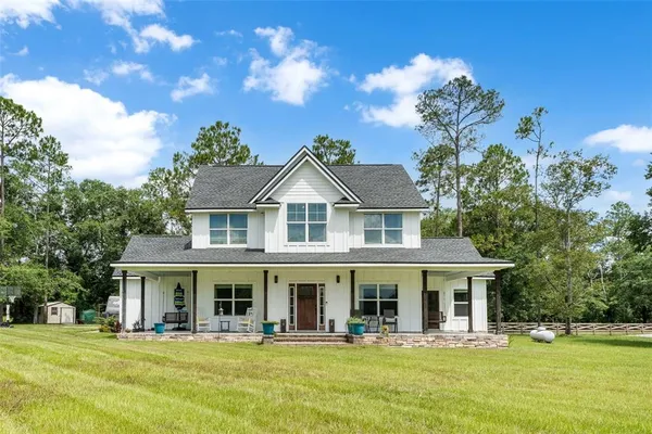 a front view of a house with swimming pool and porch with furniture