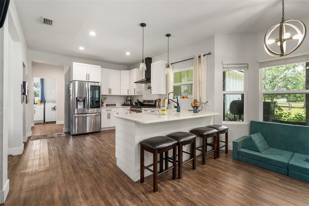 15971 Southeast 64th Street Lake Butler, FL 32054 - Photo 5 of 44 a kitchen with stainless steel appliances granite countertop a refrigerator a sink dishwasher a dining table and chairs with wooden floor