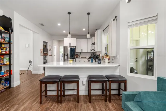 a kitchen with stainless steel appliances a dining table chairs sink and cabinets