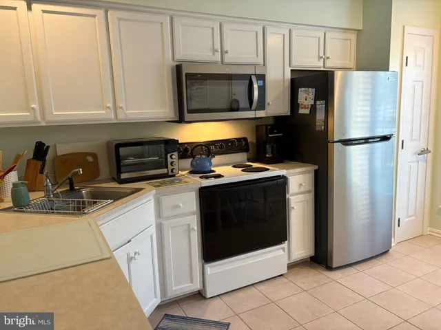 a kitchen with stainless steel appliances granite countertop white cabinets a refrigerator and a stove