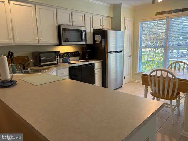 a kitchen with stainless steel appliances a refrigerator a stove a sink a table and chairs