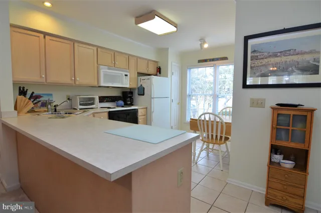 a kitchen with stainless steel appliances a stove a refrigerator a sink a dining table and chairs