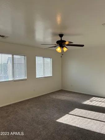 an empty room with windows and chandelier fan