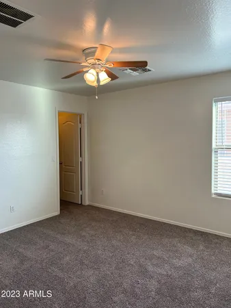 an empty room with a chandelier fan and windows