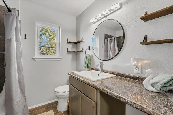 a bathroom with a granite countertop toilet a sink and a mirror